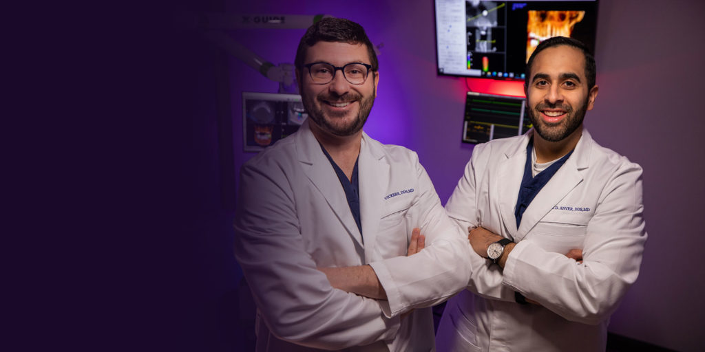 Doctors smiling on purple background with dental technology