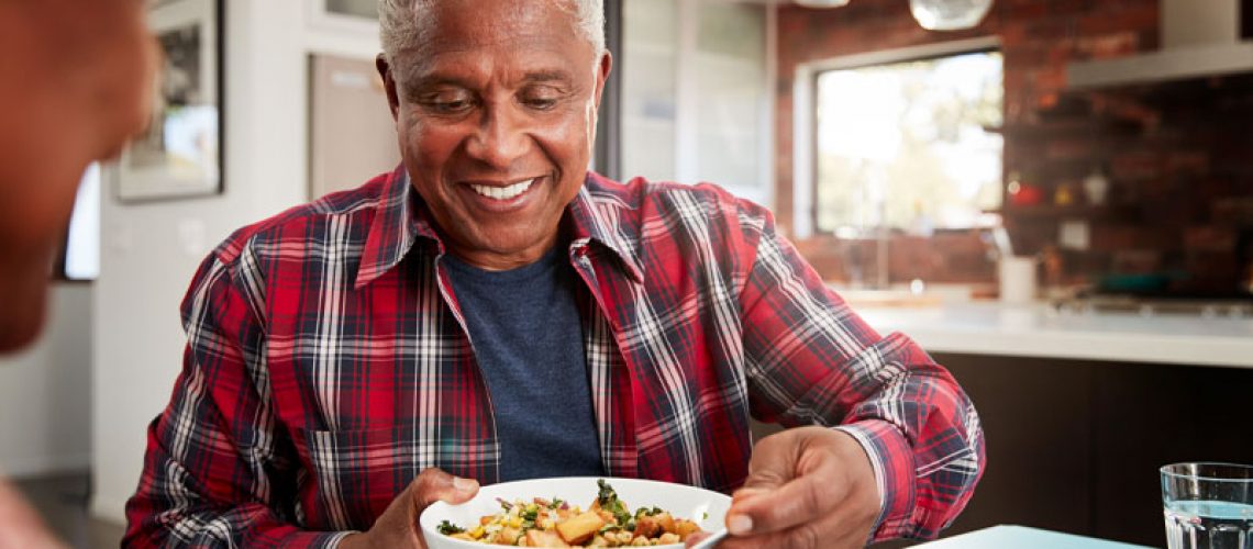 a picture of a patient smiling over his bowl of food because he went to a skilled oral surgeon for his dental implant procedure.