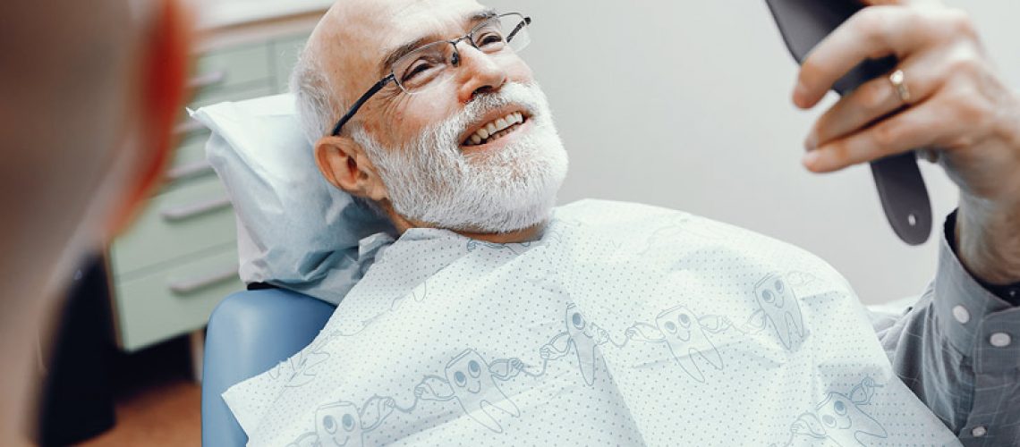 An image of an older man sitting in a dentist chair and smiling.
